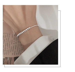 Polished S925 sterling silver ball bracelet on woman wrist over magazine