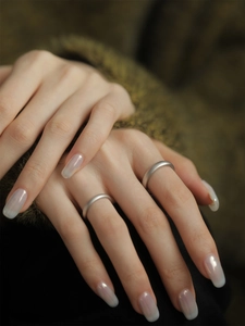 Close-up of minimalist S925 sterling silver frosted rings worn by a couple on a dark background