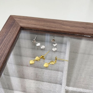 Détail des boucles d'oreilles à trois cœurs pendants en finitions or et argent