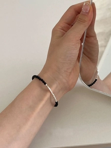 Detailed view of S925 silver beaded bracelet with black onyx stones on woman's wrist