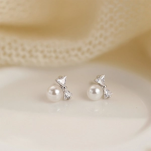 Close-up of S925 silver bow stud earrings with white pearls and sparkling zircons