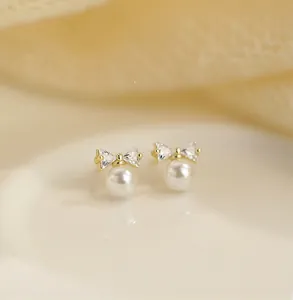 Detailed macro view of S925 silver bow stud earrings with glossy white shell pearls