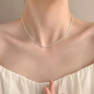 Close-up of triple-layered silver bead necklace on neck, minimalist elegant style