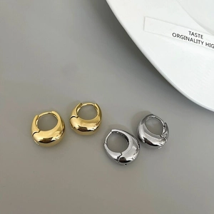 Close-up of gold and silver teardrop earrings with high-polish mirror finish surfaces