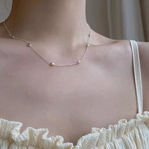 Close-up of minimalist S925 sterling silver necklace with three olive beads on collarbone