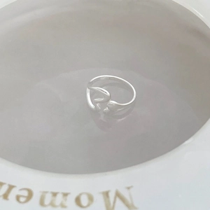Detailed top view of minimalist silver hollow heart ring on a decorative plate