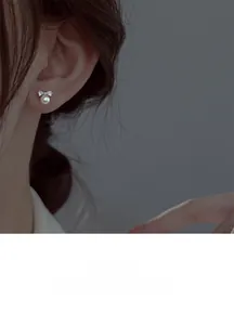 Close-up of elegant S925 silver bow earrings with white pearls worn by a model