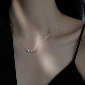 Close-up of triple bean pendants on a sleek silver snake chain worn by a model