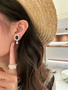 Gros plan de boucles d'oreilles rétro en onyx noir et bague mate sur le modèle