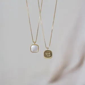 Detail showing double-sided gold square pendant with white shell and Good Luck engraving