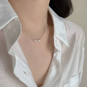 Close-up of minimalist S925 sterling silver necklace with three olive beads on a model
