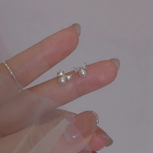 Elegant gold bow earrings with crystal triangles and round pearl shown in hand