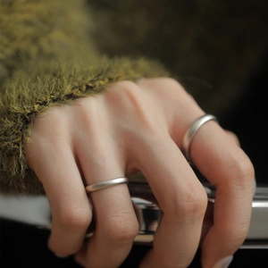 Macro shot of matte S925 sterling silver minimalist couple rings on olive green knit background