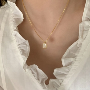 Detail of elegant gold plated necklace with a rectangular white mother of pearl pendant