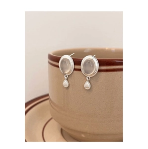 Vue macro des boucles d'oreilles vintage en argent S925 avec pierres blanches sur une tasse