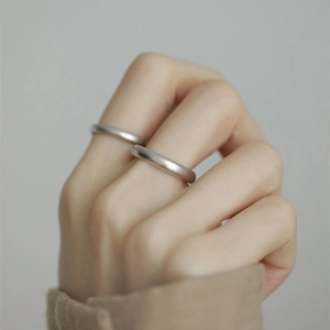 Detail view of two minimalist S925 sterling silver rings with matte frosted finish on hands