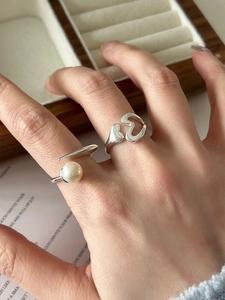 Detailed view of S925 silver hollow heart and pearl adjustable rings on a wooden box