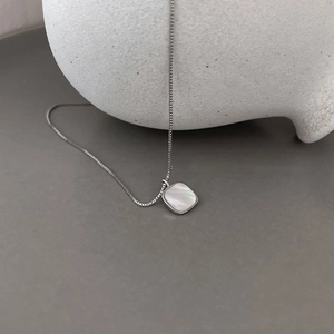 Macro shot of square white mother of pearl pendant on a S925 silver necklace