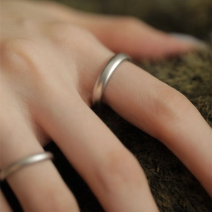 Close-up of minimalist matte S925 sterling silver couple rings worn on hand