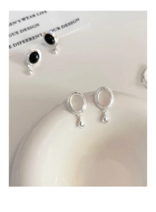 Gros plan détaillé des boucles d'oreilles goutte en argent S925 sur plat en céramique
