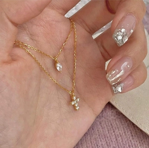 Detail einer doppellagigen Goldkette mit Kreuzanhänger, nah in der Hand für Detailansicht