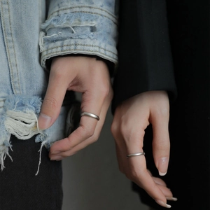 Close-up of minimalist brushed silver couple rings worn by hand in stylish attire