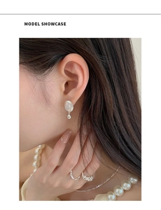 Détail de boucles d'oreilles pendantes en argent S925 avec pierre blanche portée