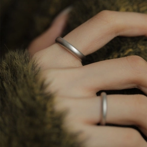 Close-up of minimalist matte S925 sterling silver couple rings on soft plush fabric