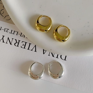 Polished silver and gold teardrop hoop earrings displayed on white ceramic plate