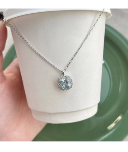 Macro detail of cushion-cut blue zircon pendant with halo diamonds on S925 silver chain
