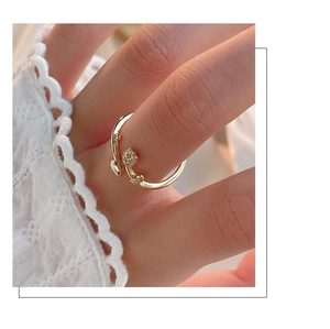 Detailaufnahme eines goldenen Tulpenrings mit weißem Zirkon an der Hand mit Spitze