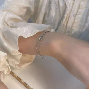 Detail of S925 sterling silver double-layer bracelet with hollow heart charm on wrist