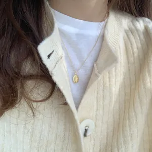 Dettaglio della collana con rosa in argento S925 dorato indossata su abbigliamento casual