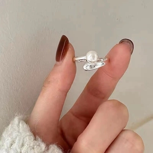 Macro detail of French style S925 silver wrap pearl ring on finger with adjustable band