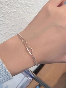 Detail view of S925 sterling silver spliced bracelet with hollow heart charm on wrist