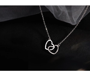 Macro shot of interlocking double heart pendant on delicate silver chain necklace