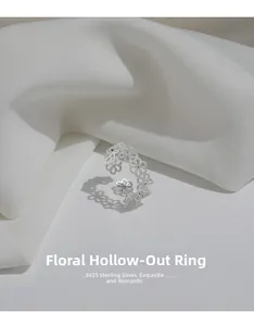 Detailed macro view of S925 sterling silver hollow flower ring on white silk background