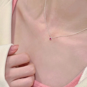 Détail d'un collier chaîne à billes en argent avec un petit pendentif cœur rouge