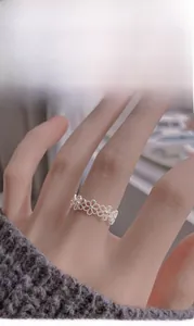 Detail shot of a silver hollow flower ring with textured matte petals on fingers