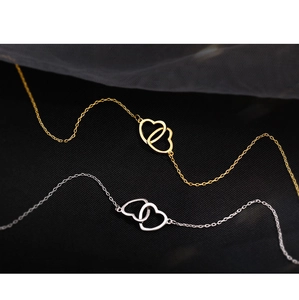 Detailed view of interconnected heart pendants in gold and silver polished finish