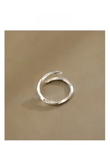 Macro detail of S925 sterling silver Mobius ring with Luck engraving on linen background