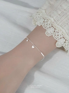 Detail of S925 sterling silver heart bracelet worn on wrist with delicate lace sleeve