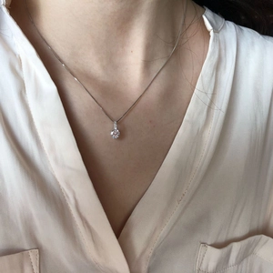 Close-up of S925 sterling silver necklace with round cut moissanite pendant on model