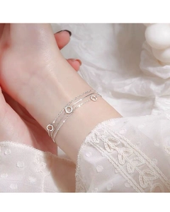 Detail of a minimalist triple-layer silver bead bracelet with hollow circular charms