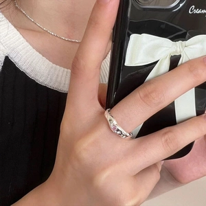 Detailed view of an irregular silver ring with pink heart stones worn on finger