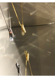 Macro shot of interlocking geometric silver and gold necklaces with micro-set zircons