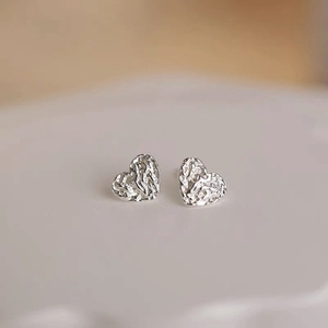 Macro detail of heart-shaped silver earrings with unique crinkled foil metal texture