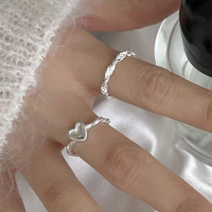 Close-up of S925 sterling silver twist rings with heart charm on silk background