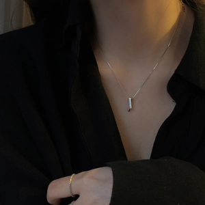 Close-up of minimalist S925 sterling silver interlocking rectangle necklace and diamond ring