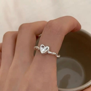 Detailed view of an S925 sterling silver heart ring with twisted band on a finger